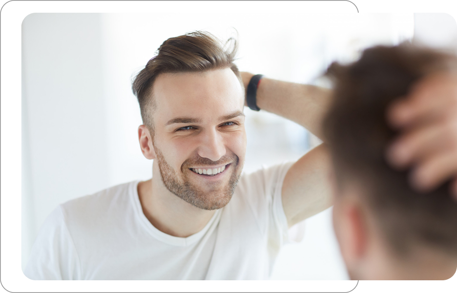 Uśmiechnięty mężczyzna przeglądający się w lustrze i przeczesujący włosy dłonią, efekt zadbanego wyglądu i pielęgnacji męskiej.