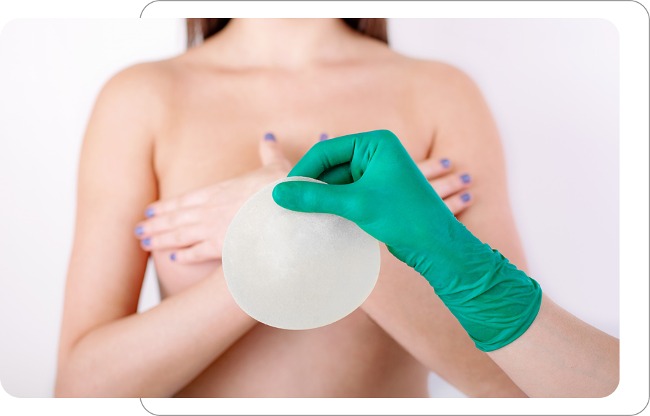 Kobieta zasłaniająca piersi dłońmi podczas konsultacji, a specjalista prezentuje implant piersiowy w zielonej rękawiczce.