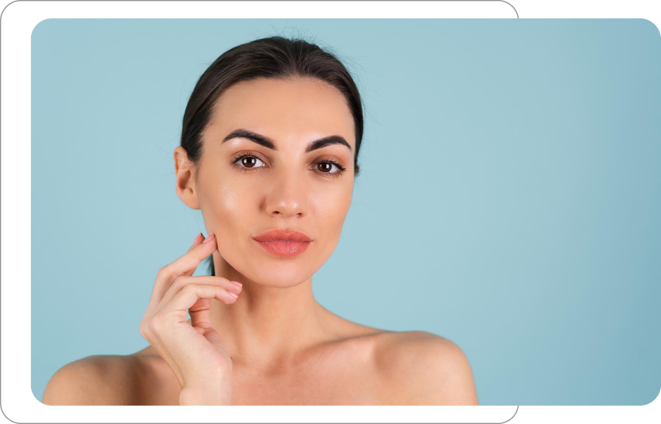 Kobieta z gładką, zadbaną cerą dotykająca policzka, prezentująca efekty zabiegów pielęgnacyjnych i medycyny estetycznej na twarz.