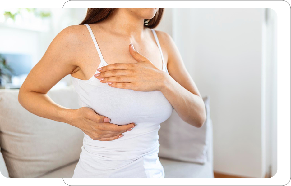 Kobieta w białej koszulce podtrzymująca piersi dłonią podczas samobadania lub konsultacji estetycznej biustu.